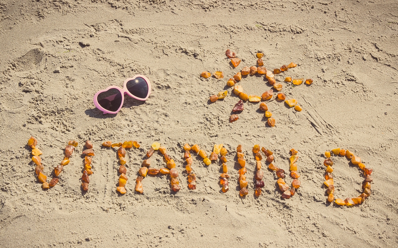 Ein Schriftzug Vitamin D im Sand und eine Sonne