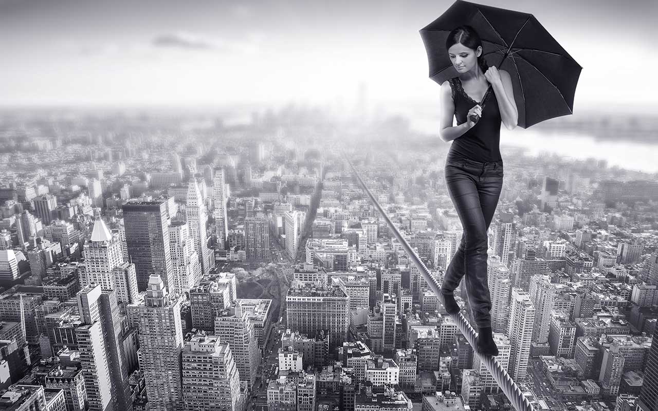 Eine Frau, die über einer Stadt auf einem Drahtseil balanciert als Symbol für Angst bei Albträumen