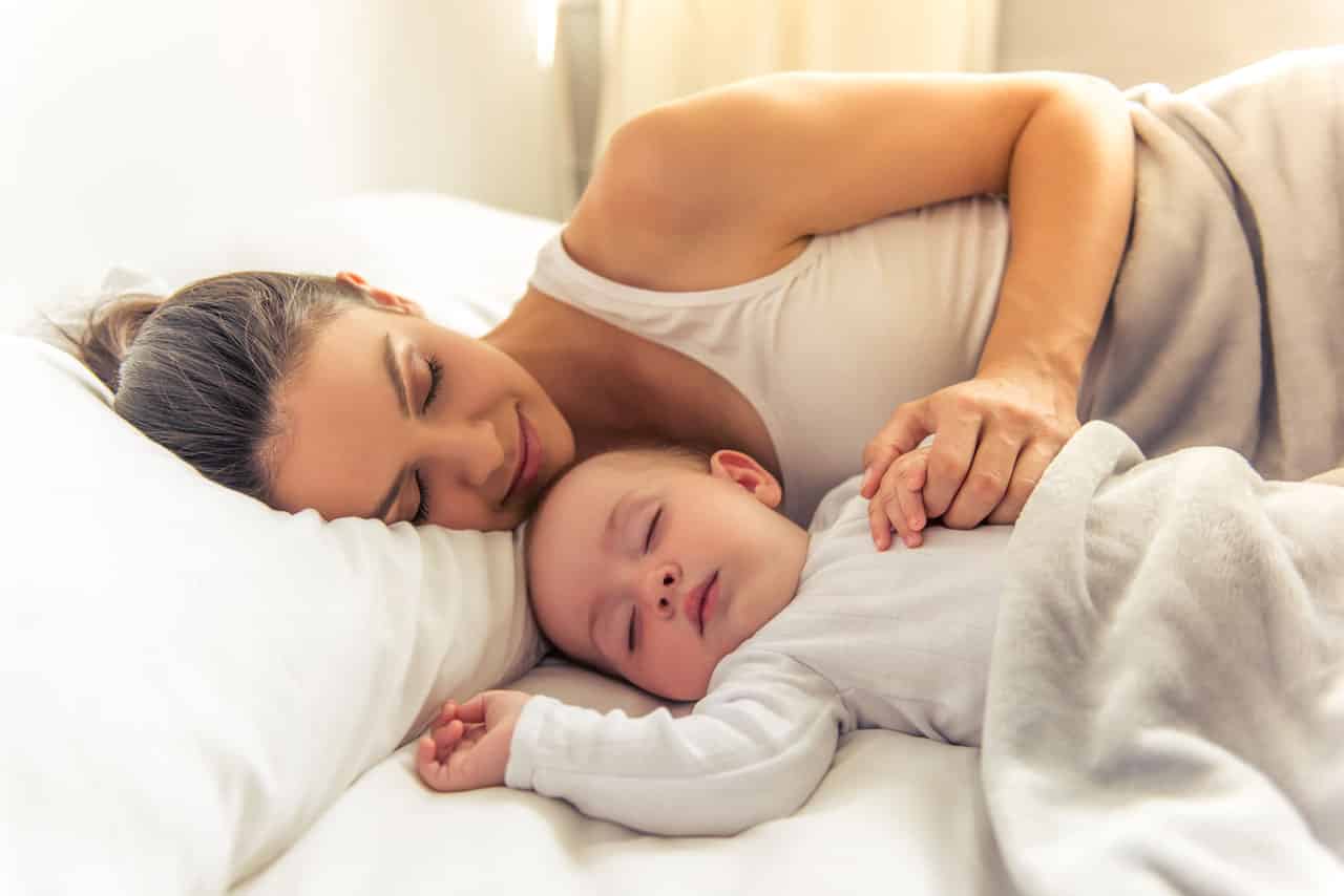 Eine Mutter mit ihrem Baby im Bett, sie ist glücklich, da sich der Kinderwunsch erfüllt hat