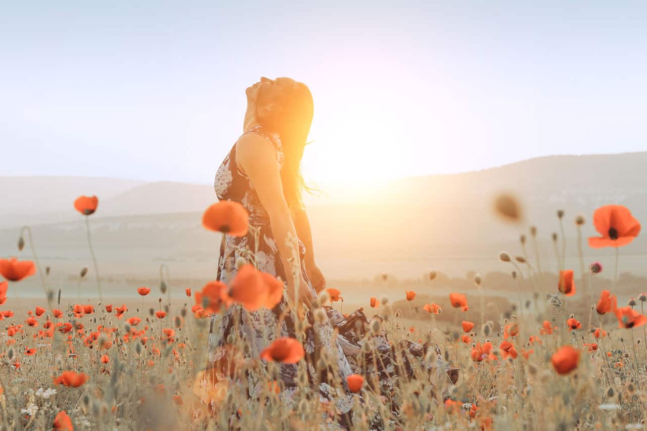 Eine Frau in einem Mohnblumenfeld, die frei durchatmet