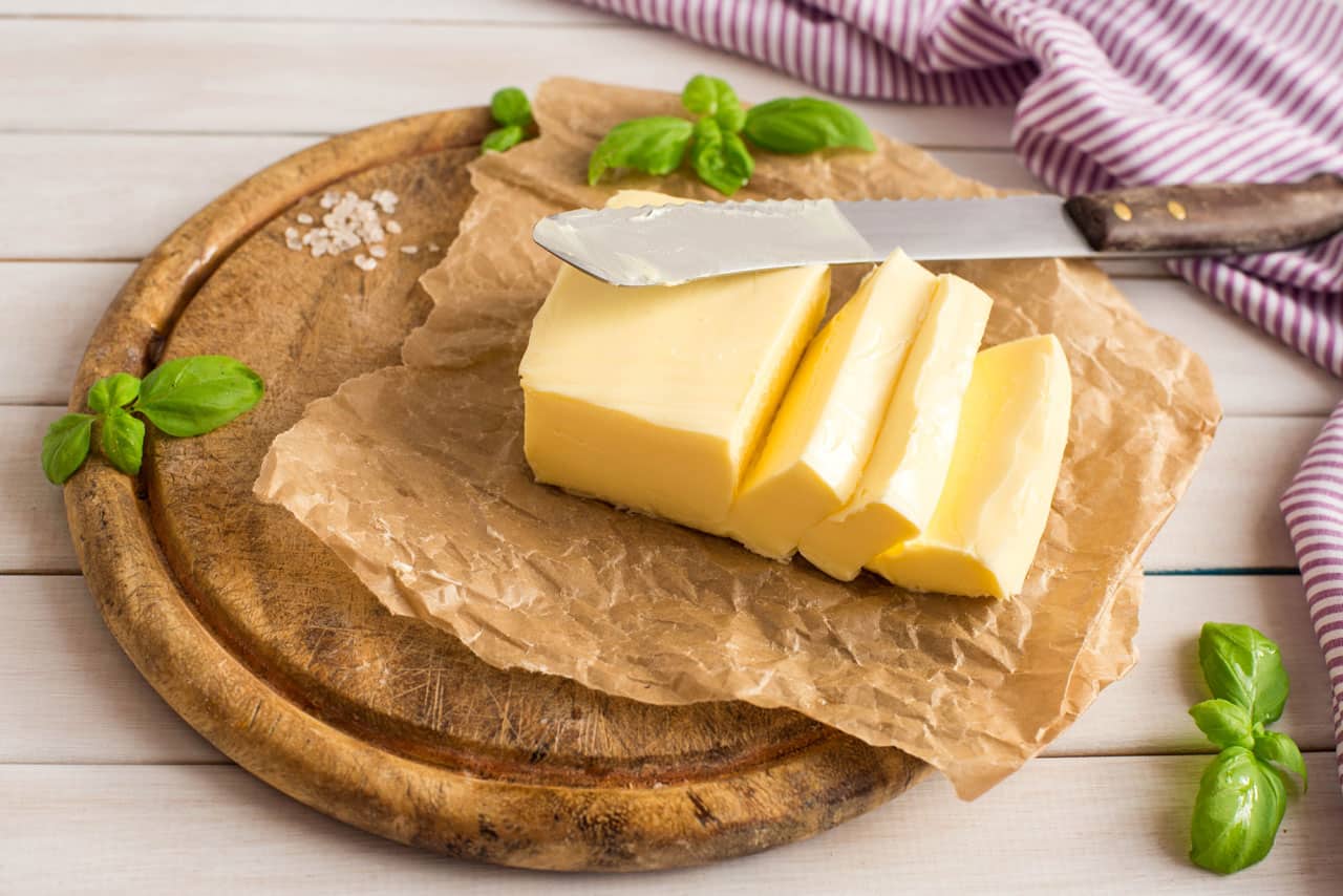 Ein Stück Butter auf einem Brett als Symbol für eine fettreiche Ernährung