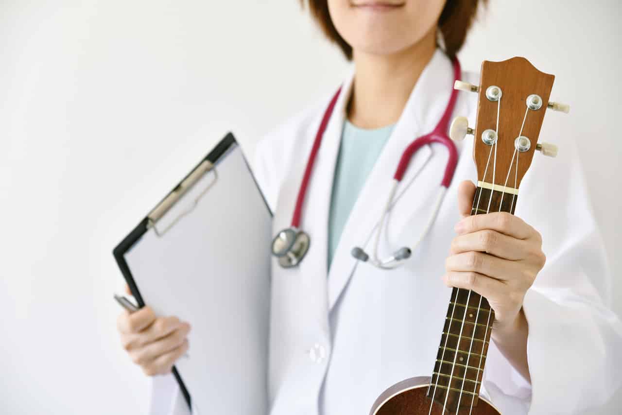 Eine Ärztin bei der Musiktherapie mit einer Ukulele in der Hand