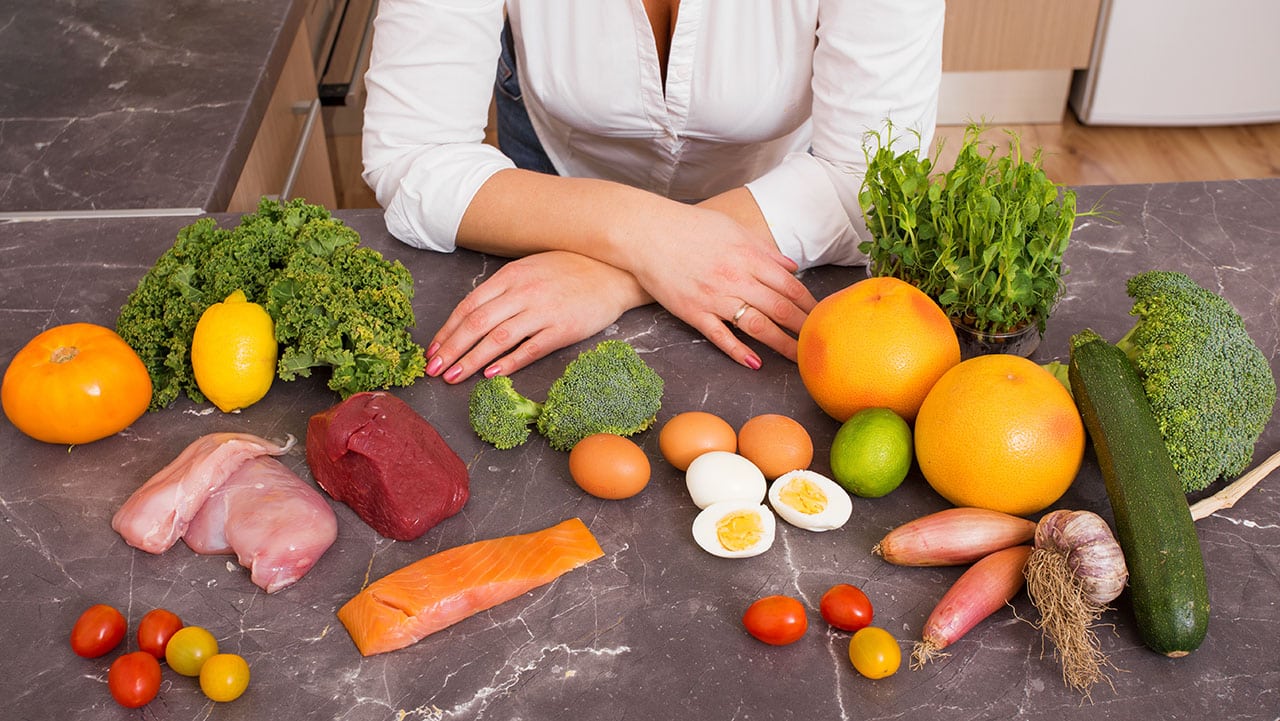 Auf einem Tisch liegen Low Carb Lebensmittel wie Fisch, Eier, Fleisch und Gemüse.